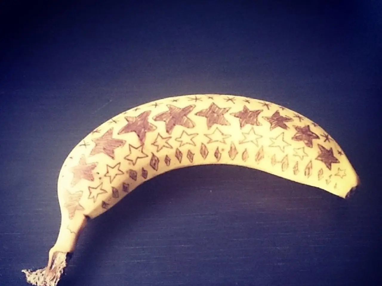 This image consist of a banana which is on the black colour surface.