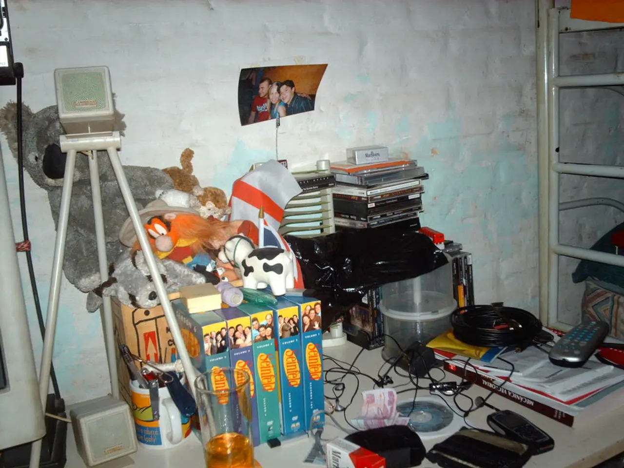 In the image there are books,remote,earphones,cash,cups,tripod,photography,toys on a table, in...