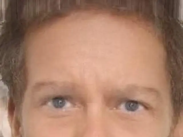 In the center of the image there is a man. At the bottom of the image there is text.