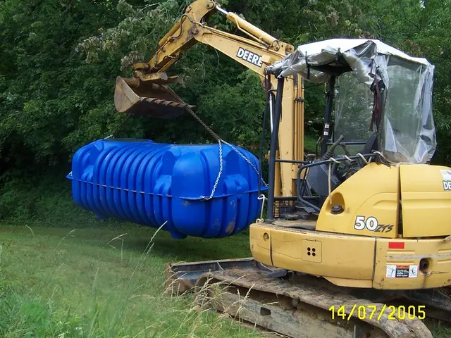 In this picture I can observe yellow color crane on the ground. This crane is lifting large blue...